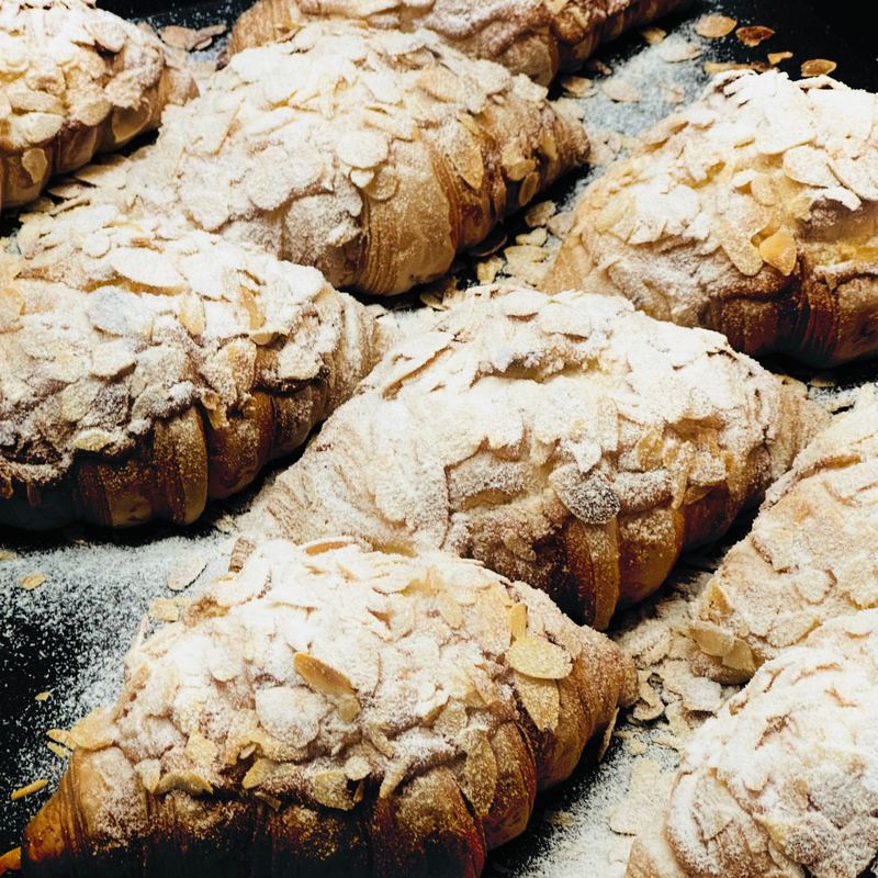 An almond croissant topped with flaked almonds and icing sugar