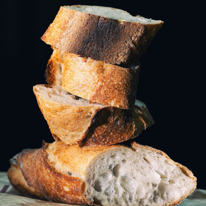 Two golden French baguettes resting on a linen cloth